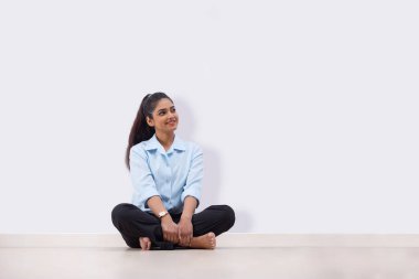 Young business woman in formal outfit sitting on floor and looking elsewhere clipart