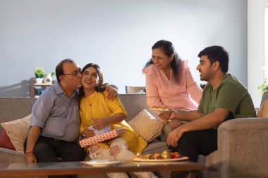 Baba, Raksha Bandhan 'da ailesiyle birlikte otururken kızına bakıyor.