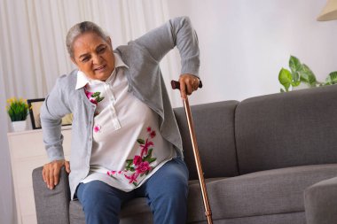 Kıdemli kadın bastonun yardımıyla tek başına ayakta durmaya çalışıyor.