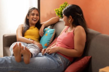 Oturma odasındaki kanepede dinlenen iki genç kadın.