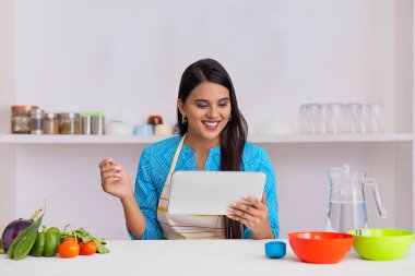 Hintli kadın yemek tarifini mutfakta tabletten öğreniyor.