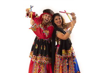 Navratri kutlamaları sırasında Dandiya Raas 'ı sergileyen mutlu genç çiftin portresi.