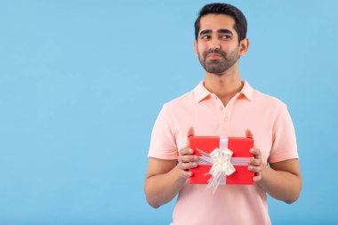 Elinde bir hediyeyle başka bir yere bakan genç adamın portresi.