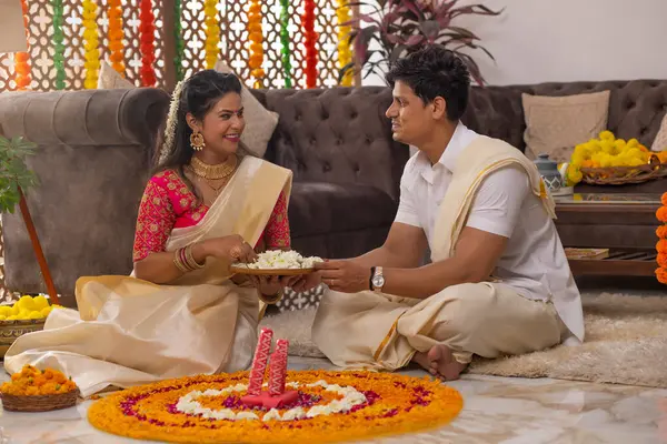 Güney Hintli çift Onam 'ı kutlamak için çiçek çelengi ile evi dekore ediyorlar.