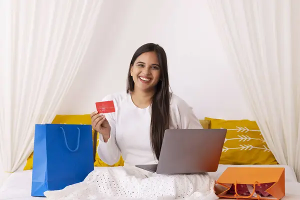 stock image Indian girl showing her debit card during online shopping through laptop in bedroom