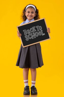 Okul üniformalı bir kız salgından sonra okula dönüş mesajını mutlulukla iletiyor.