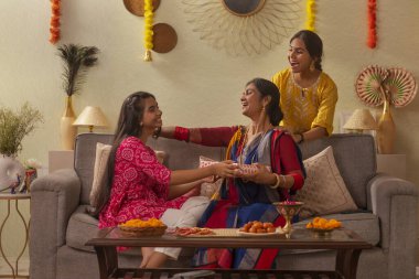 Durga Puja vesilesiyle oturma odasında kanepede otururken Bengali ailesi hediyelerini değiş tokuş ediyor.