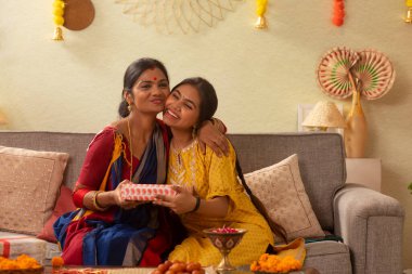 Anne kızına hediye veriyor ve okşuyor.