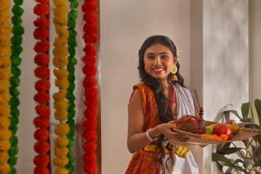 Durga Puja vesilesiyle Puja Thali 'nin yanında duran beyaz elbiseli Bengalli kadın.