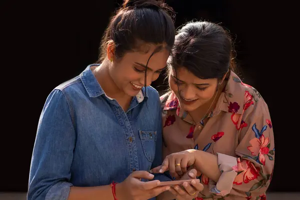 stock image Two young women using mobile phone together