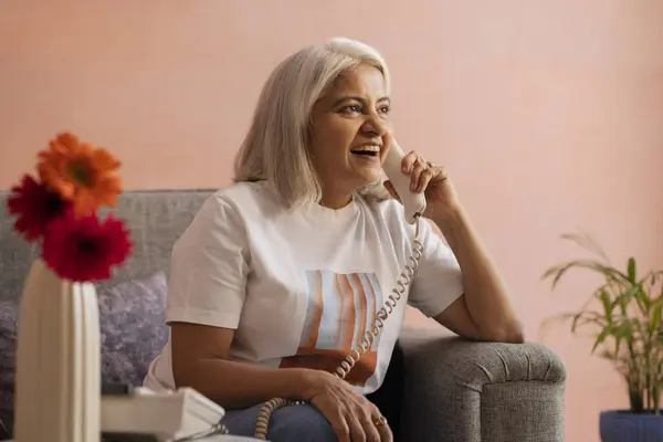 stock image Happy old woman talking on telephone in living room