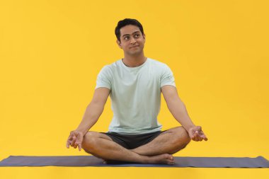 Evde meditasyon yapan genç bir adamın portresi.