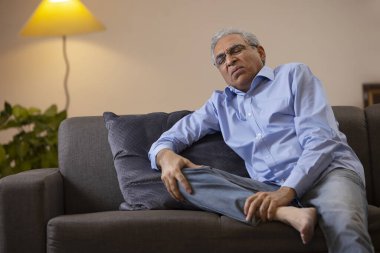 Diz ağrısı çeken yaşlı bir adamın portresi.