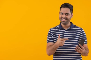 Genç adam kameranın önünde elinde Smartphone ile poz veriyor.