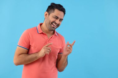 Kameraya bakıp başka bir yeri gösteren gülümseyen genç adamın portresi.