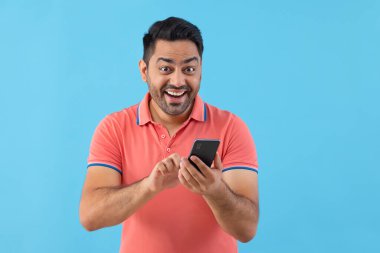 Smartphone kullanırken kameraya bakan mutlu genç adamın portresi