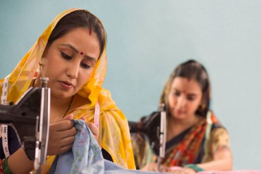 Dikiş makinelerinde çalışan iki kırsal kadın..