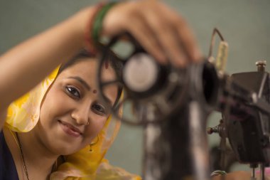 Bir dikiş makinesi ile çalışan bir kadın.