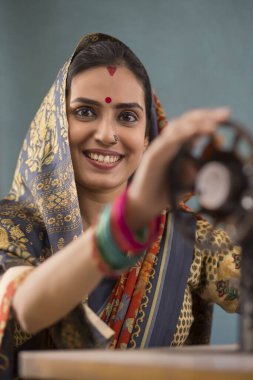 A woman grinning with a sewing machine. clipart