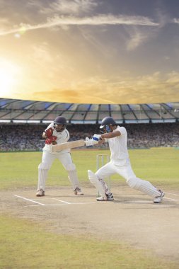 Kriket vurucusu sahadaki bir maçta atış yapıyor.