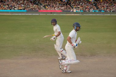 Kriket oyuncuları ve vurucular maçta koşarken birbirlerine çarpıyorlar.