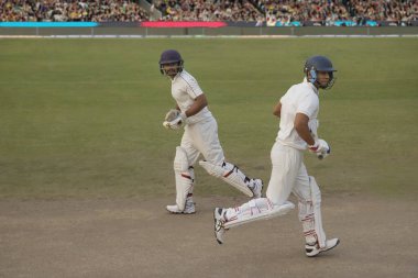 Cricketers, batsmen cross eaching other while taking a runduring a match clipart