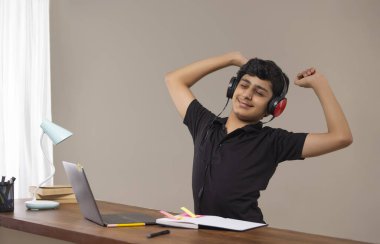 A TEENAGE BOY STRETCHING WHILE ATTENDING ONLINE CLASS clipart