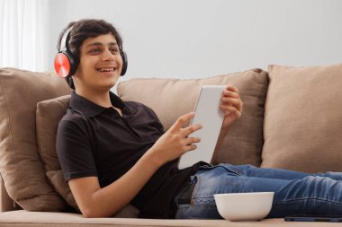 Dijital masayı evde kullanırken, mutlu bir ergen gökyüzüne bakıyor.