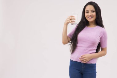 Elinde bir bardak sütle ayakta duran bir ergen.