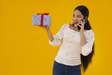 Elinde hediyeyle telefonda konuşan bir kadın..