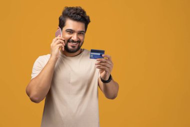 Cep telefonuyla konuşan ve arka planda kredi kartı tutan bir adamın portresi..