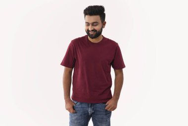 Bıyıklı genç bir adam ayakta duruyor ve gülümsüyor.