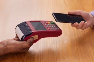 İki el bir geçiş makinesi ve cep telefonu tutuyor..