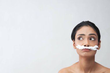 Yüzünde tüy dökücü krem olan genç bir kadın..