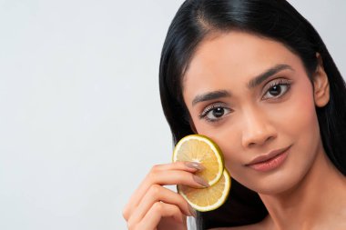 A young woman with clear,spotless skin holding two slices of  lemon. clipart