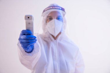 PPE kiti takmış bir sağlık çalışanı ateşini kontrol ediyor..