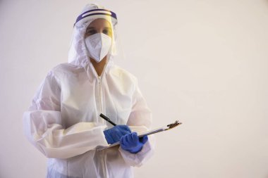 A health worker in PPE kit holding a notepad and pen. clipart