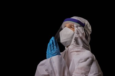 PPE kiti içinde bir doktor dua için el ele tutuşuyor..