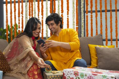 Yakışıklı genç bir adam telefonunda güzel bir kıza fotoğraf gösteriyor.