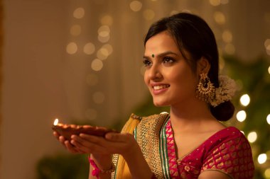 Beautiful woman adoring a diwali diya clipart