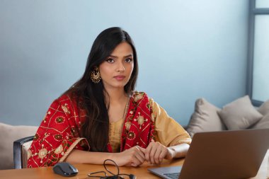 Young girl sitting on a desk with her laptop clipart