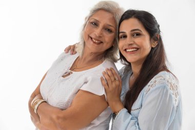 A SENIOR ADULT WOMAN AND DAUGHTER SMILING AND LOOKING AT CAMERA clipart