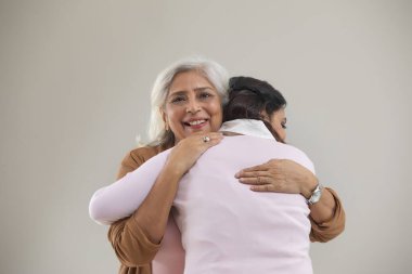 A MOTHER HUGGING ADULT DAUGHTER IN HAPPINESS clipart