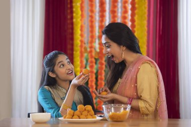 Daughter offering sweets to her mother clipart