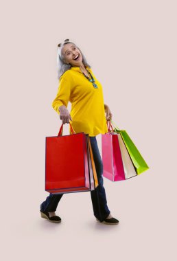 An old woman happily holding colorful carrybags. clipart