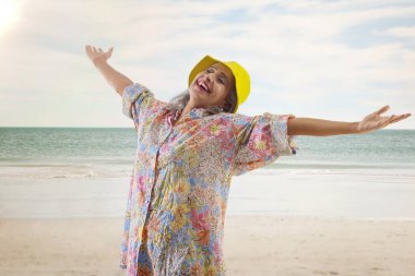 Kumsalda güneşlenen yaşlı bir kadın.