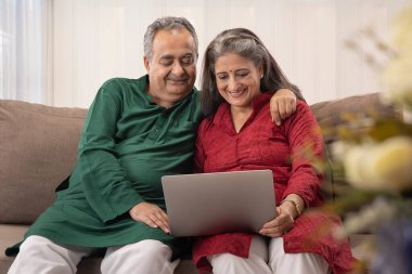 A HAPPY HUSBAND AND WIFE SITTING TOGETHER AND USING LAPTOP clipart