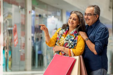 A HAPPY COUPLE STANDING TOGETHER AND LOOKING AT SHOPS clipart