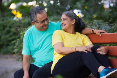 A HAPPY HUSBAND AND WIFE SITTING TOGETHER AND LOOKING AT EACH OTHER clipart