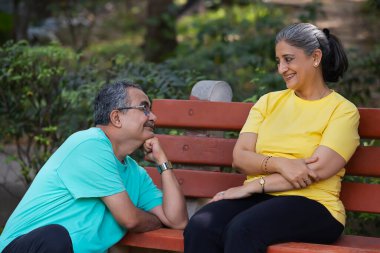 AN OLD MAN LOVINGLY LOOKS AT WIFE WHILE SITTING BELOW HER clipart